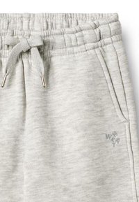 Los pantalones deportivos gris claro cuentan con una cintura elástica acanalada con cordón, bolsillos laterales y un pequeño detalle de logotipo cerca del dobladillo.