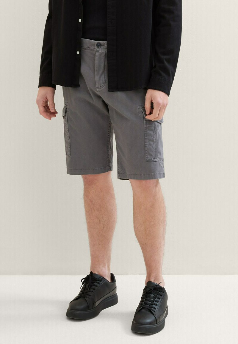 Gray cargo shorts made from cotton blend, featuring side pockets, a relaxed fit, and hem finishing. Paired with black sneakers.