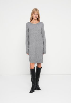 Robe en tricot gris à manches longues et ourlet côtelé, associée à des bottes noires jusqu'aux genoux. Sa texture douce et sa coupe décontractée augmentent le confort.