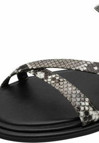 Sandale noire avec des brides croisées en motif peau de serpent gris et blanc sur une semelle lisse.
