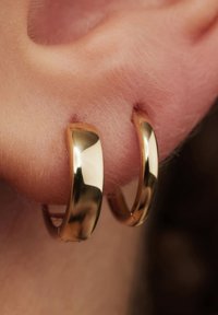 Goldene Creolen mit glatter und glänzender Oberfläche, leichtem Design, mittlerer Größe, in einfacher, runder Form und polierter Oberfläche.