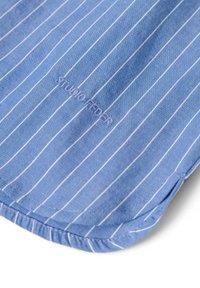 Hellblau gestreiftes Hemd mit weißen vertikalen Linien, versehen mit einem gestickten Etikett "STUDIO FEDER." Der Stoff hat eine glatte Textur.