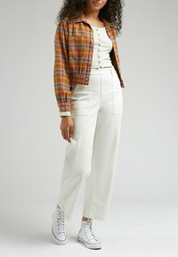 Cropped orange plaid jacket with button closure, white ribbed top, and high-waisted white pants. White high-top sneakers complete the look.