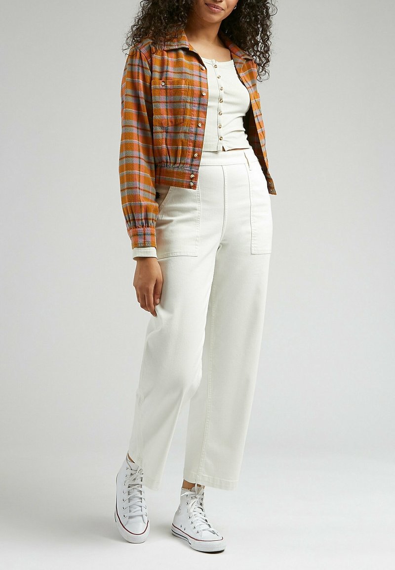 Cropped orange plaid jacket with button closure, white ribbed top, and high-waisted white pants. White high-top sneakers complete the look.