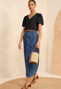 Melnas viļņotas blūzes ar pūkainām piedurknēm, augsto vidukļa džinsu svārku, brūnu jostu, brūnas slaidās papēžus un austu rokas somu.