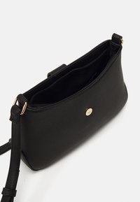 Czarna, usztywniana torebka wykonana z teksturowanego materiału. Wyposażona w złote okucia i otwierana na zamek, z regulowanym paskiem na ramię.