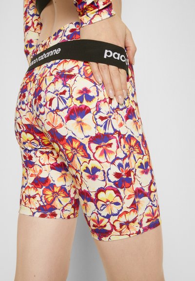 Bermuda com padrão floral e um cós elástico preto com o logótipo "paco rabanne". As cores incluem amarelo, vermelho, púrpura e creme. Tecido elástico.