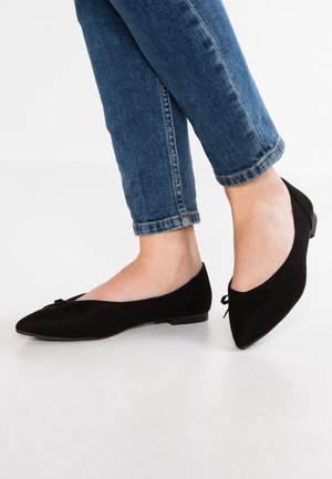 Bailarinas de ante negro con puntera afilada y un pequeño detalle de lazo. Combinadas con unos jeans cropped azules, que realzan el diseño elegante de los zapatos.