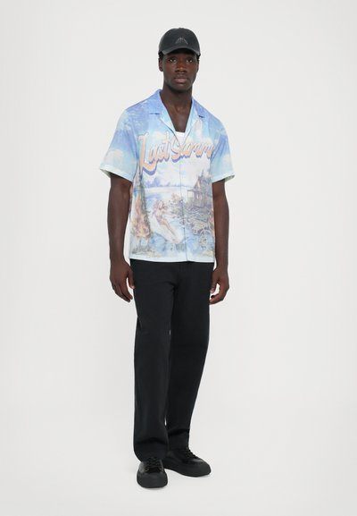 Short-sleeve, light blue shirt featuring a colorful scenic print and text "Last Summer"; matched with black, straight-leg pants and black shoes.