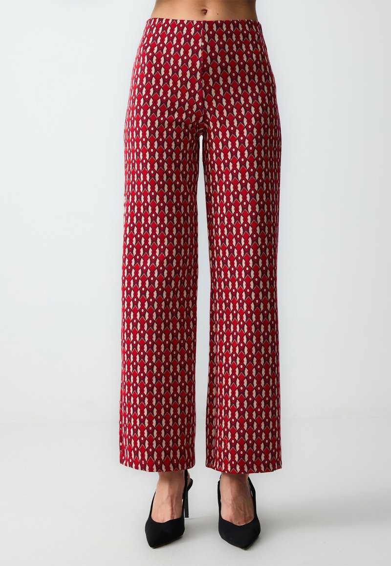 Pantaloni a gamba larga realizzati in tessuto con un motivo geometrico rosso e beige, dotati di vita alta e finitura testurizzata.