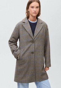 Rjav in modernega modrega karirane plašč z velikimi ovratniki, gumbnim zapiranjem in stranskimi žepi, izdelan iz teksturiranega materiala, oblikovan za sproščen fit.