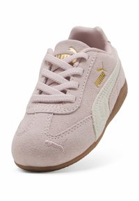 Zapatillas de ante rosa claro con acentos blancos, que presentan una suela de goma texturizada, diseño de cordones y el logo dorado de Puma en el costado y en la lengüeta.
