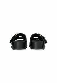 Black sandals with a chunky heel, featuring adjustable straps and gold-tone hardware. Smooth texture, open back design.