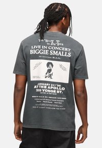 Černé bavlněné tričko s koncertní grafikou Biggie Smalls na zadní straně, včetně textu, fotografie a údajů o akci. Krátké rukávy.