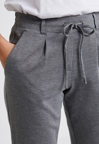 Grå sweatpants med en texturerad tyg, elastisk midjeband, dragsko stängning och sidofickor. Designad med en avslappnad passform och veckad fram.