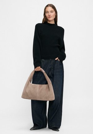 Beige suede shoulder bag with a curved top handle, paired with a black ribbed sweater and wide-leg dark denim jeans.