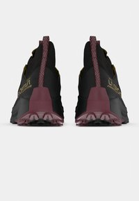 Trekka skriešanas apavi ar melnu virsu, bordo ārējo zoli un rakstainiem cilpas. Aprīkoti ar pastiprinātu papēdi un teksturētām virsmām labākai saķerei.