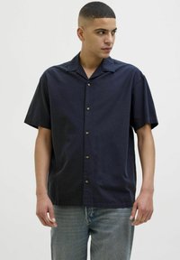 Camisa de botones de manga corta en color marino, fabricada en tejido ligero, con un corte relajado, un cuello tipo camp y botones marrones como detalle.