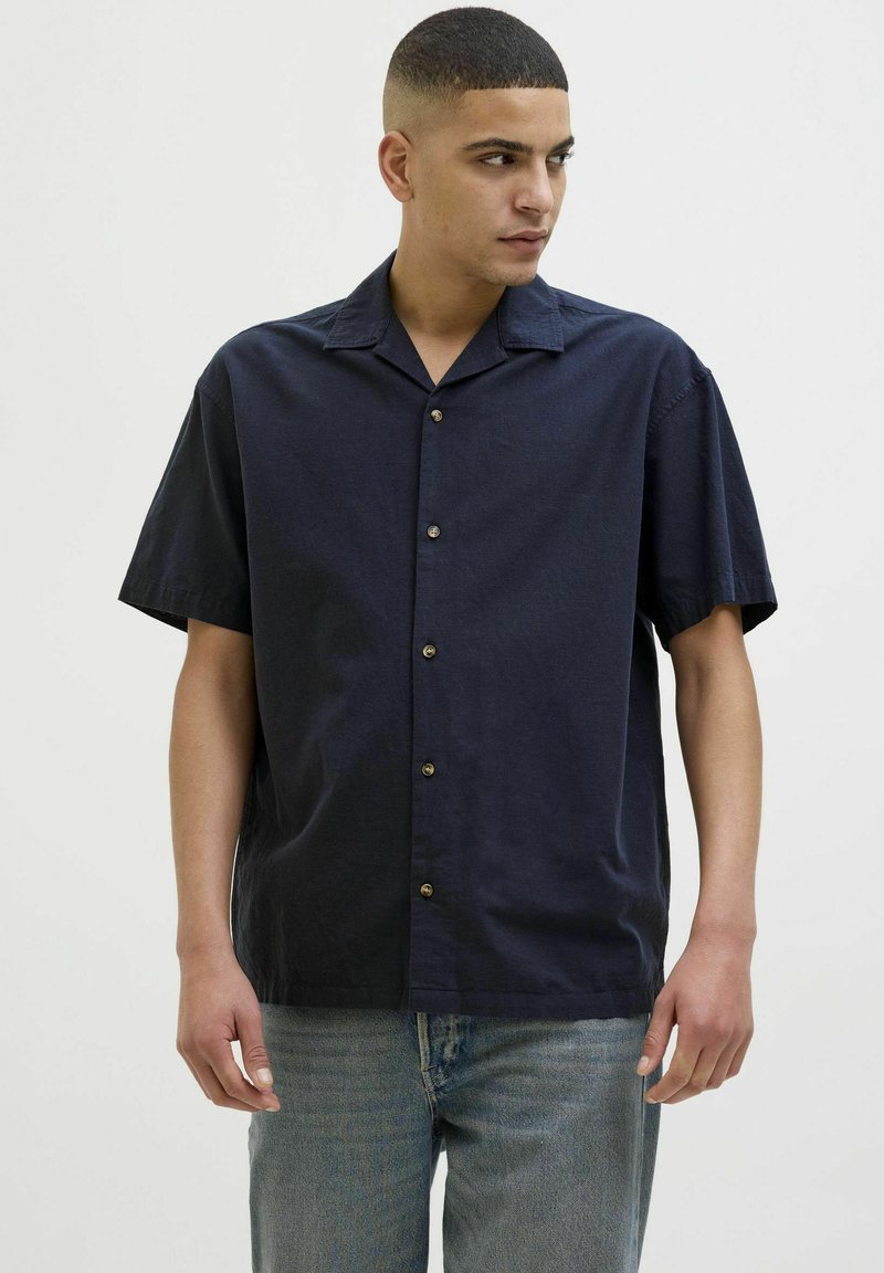 Camisa de botones de manga corta en color marino, fabricada en tejido ligero, con un corte relajado, un cuello tipo camp y botones marrones como detalle.