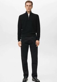 Czarny sweter na zamek z teksturowanym splotem, zestawiony z czarnymi spodniami o prostych nogawkach i czarnymi wypolerowanymi butami. Prosty i elegancki strój.