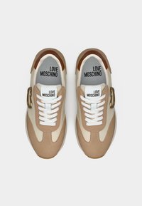 Ζευγάρι μπεζ και κρεμ αθλητικά παπούτσια με κορδόνια, με καφέ λεπτομέρειες, χρυσή αγκράφα και τυπωμένο το "LOVE MOSCHINO" στις εσωτερικές σόλες και τη γλώσσα τους.