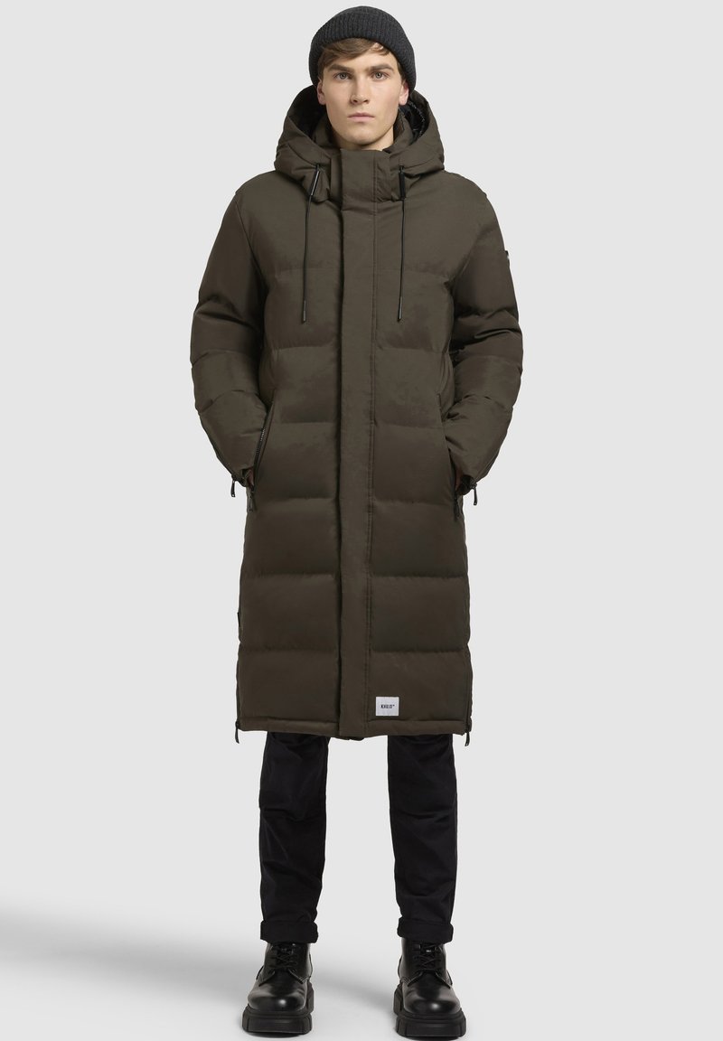gevoerde parka in donkergroen, met een capuchon, ritszakken, verstelbare trekkoorden en een logopatch aan de onderrand.