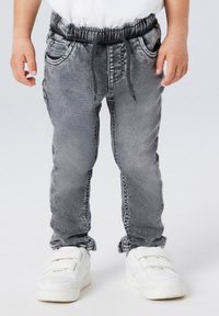 Grå joggebukse i denim med elastisk midjebånd, justerbar snor, fem lommer og en lett slitt finish.