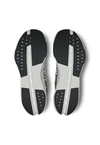 Semelles de chaussures de course avec un dessus blanc, des accents gris et un talon en caoutchouc noir texturé. Des trous de drainage notables et un design de motif unique.