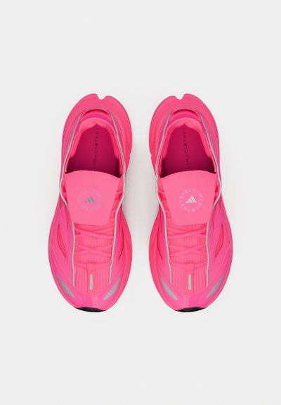 Ροζ αθλητικά παπούτσια με υφασμάτινο επάνω μέρος, τμήματα από δίχτυ, ανακλαστικές λεπτομέρειες και σχεδιασμό που αγκαλιάζει το πόδι. Διαθέτουν σύστημα κορδονιών και λογότυπο στη γλώσσα του παπουτσιού.