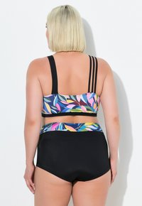 Černé bikiny s vysokým pasem a pasem se vzorem tropických listů v několika barvách, doplněné o odpovídající krátký top s třemi černými pruhy.