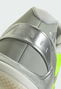 Gray athletic shoe with silver accents. Features textured paneling, mesh fabric, and a prominent "PAD" logo on the heel. Neon green details.
