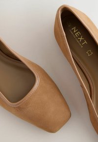 Tan ruskinds støvler med firkantet tå, der har en glat lædertrim langs åbningen og en polstret indersål mærket "NEXT Forever Comfort."