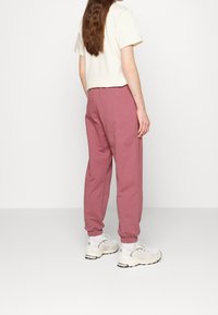 Sopiva, lyhyt vaalean kermanvärinen t-paita yhdistettynä löysiin vaaleanpuniisiin collegehousuihin, joissa on elastiset hihnat, ja lisäksi kevyet harmaat urheilukengät.