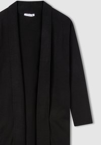 Cardigan lungo nero con apertura frontale, realizzato in un tessuto morbido. Presenta maniche lunghe e una finitura testurizzata.