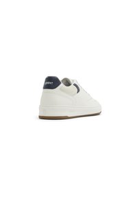 White sneaker with textured sides, navy accents on the heel and side, and a gum rubber sole. Features a stitched toe and lace-up design.