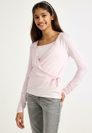 Haut cache-cœur à manches longues rose clair avec un détail noué à la taille et un décolleté en U, superposé à un t-shirt assorti à manches courtes.