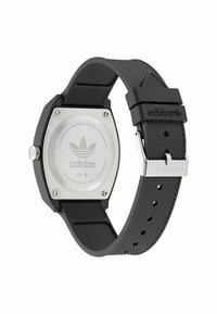 Montre avec bracelet en caoutchouc noir et boîtier en acier inoxydable octogonal. Le fond argenté présente le logo de la marque. Bracelet texturé avec boucle métallique ajustable.