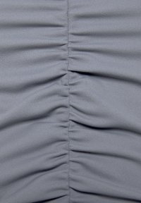 Grijze stof met verticale ruche-details, gekenmerkt door een gladde, gestructureerde oppervlakte en gedefinieerde lijnen, die subtiele diepte en dimensie creëren.