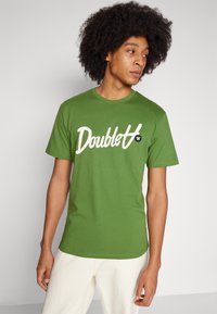 Green cotton t-shirt with a rounded neckline, short sleeves, featuring white "Doublet" text and a small black logo on the chest.