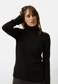 Schwarzer Rollkragenpullover aus weichem Stoff, mit einem gerippten Kragen und Bündchen, geradem Saum und langen Ärmeln.