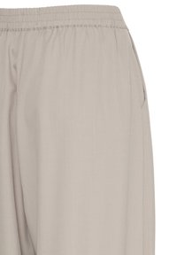Pantalon beige clair avec ceinture élastique et poches latérales, présenté de la taille à mi-cuisse sur un fond blanc uni.