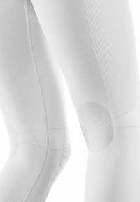 Witte compressieleggings met textuurpanelen bij de knieën, ribbelstukken en platte naden, die een gladde, strak aansluitende pasvorm laten zien.