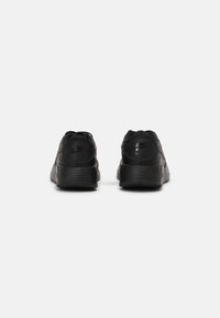 Chaussures de sport noires avec une tige texturée, un bout rond, un col rembourré et des semelles en caoutchouc épaisses. Présente un logo subtil sur le talon.