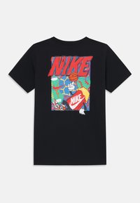 Čierne tričko s farebnou grafikou karikatúrneho basketbalistu držiaceho loptu, s nápisom "NIKE" vystupujúcim do popredia.