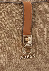Borsa a tracolla marrone con motivo, tessuto texturizzato, dettagli in pelle color nocciola e logo dorato. Presenta una chiusura in metallo lucido e cuciture a contrasto.