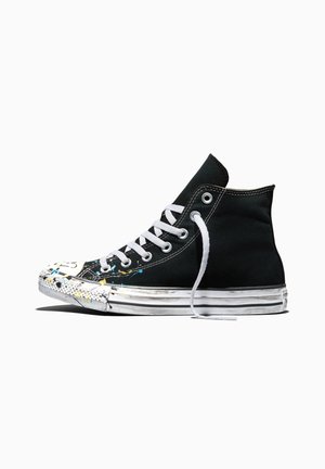 Sneaker in tela nera alta con lacci bianchi, occhielli metallici e suola in gomma bianca con schizzi di vernice colorata nell'area delle dita.