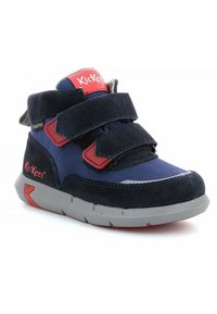 Zapatillas impermeables Kickers para niños, en azul marino y rojo, con dos correas de Velcro y suela gris, vistas desde un ángulo a la izquierda.