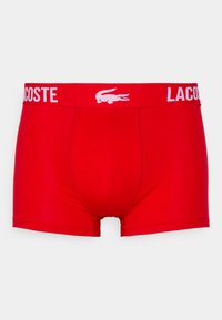Boxer-briefs rouges en coton avec une ceinture blanche logo Lacoste et un emblème de crocodile, présentant un ajustement snug et une texture lisse.
