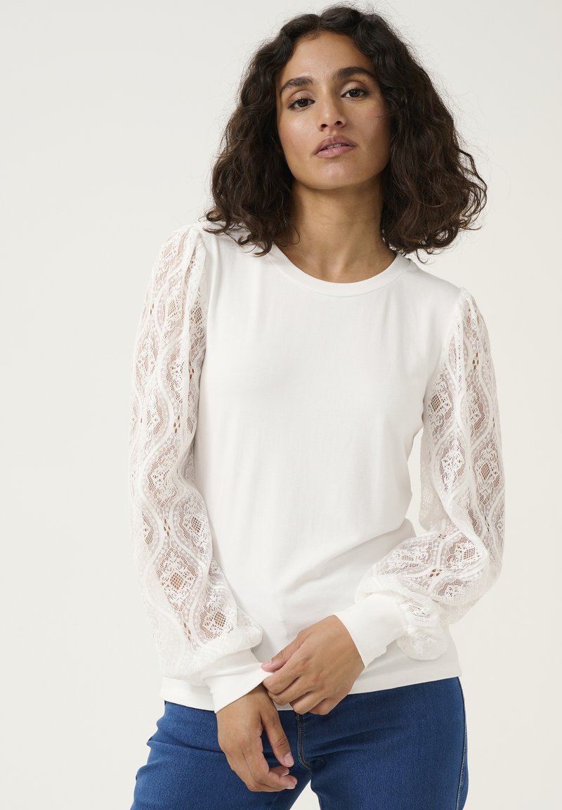 White long-sleeve shirt with lace puff sleeves and a rounded neckline. Fitted body, smooth fabric, and ribbed cuffs at the hem.