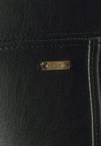 Portafoglio in pelle nera con finitura texturizzata, piastra del marchio in tono oro e cuciture a contrasto lungo i bordi. Design compatto ed elegante.